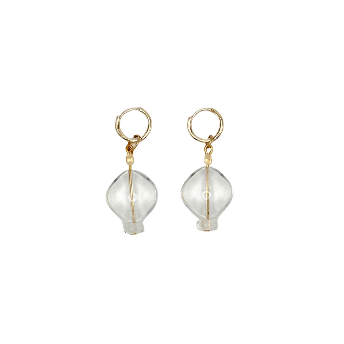 Pair of gold earrings with clear glass beads on a light gray background