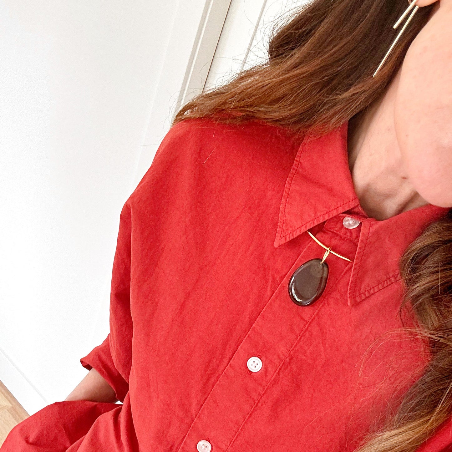 Person wearing a red shirt with a close-up of the collar and buttons.