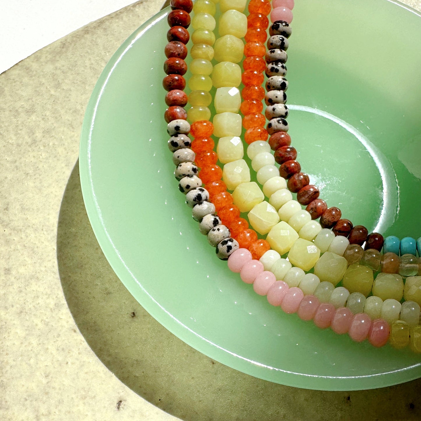 Colorful beaded necklaces on a green plate