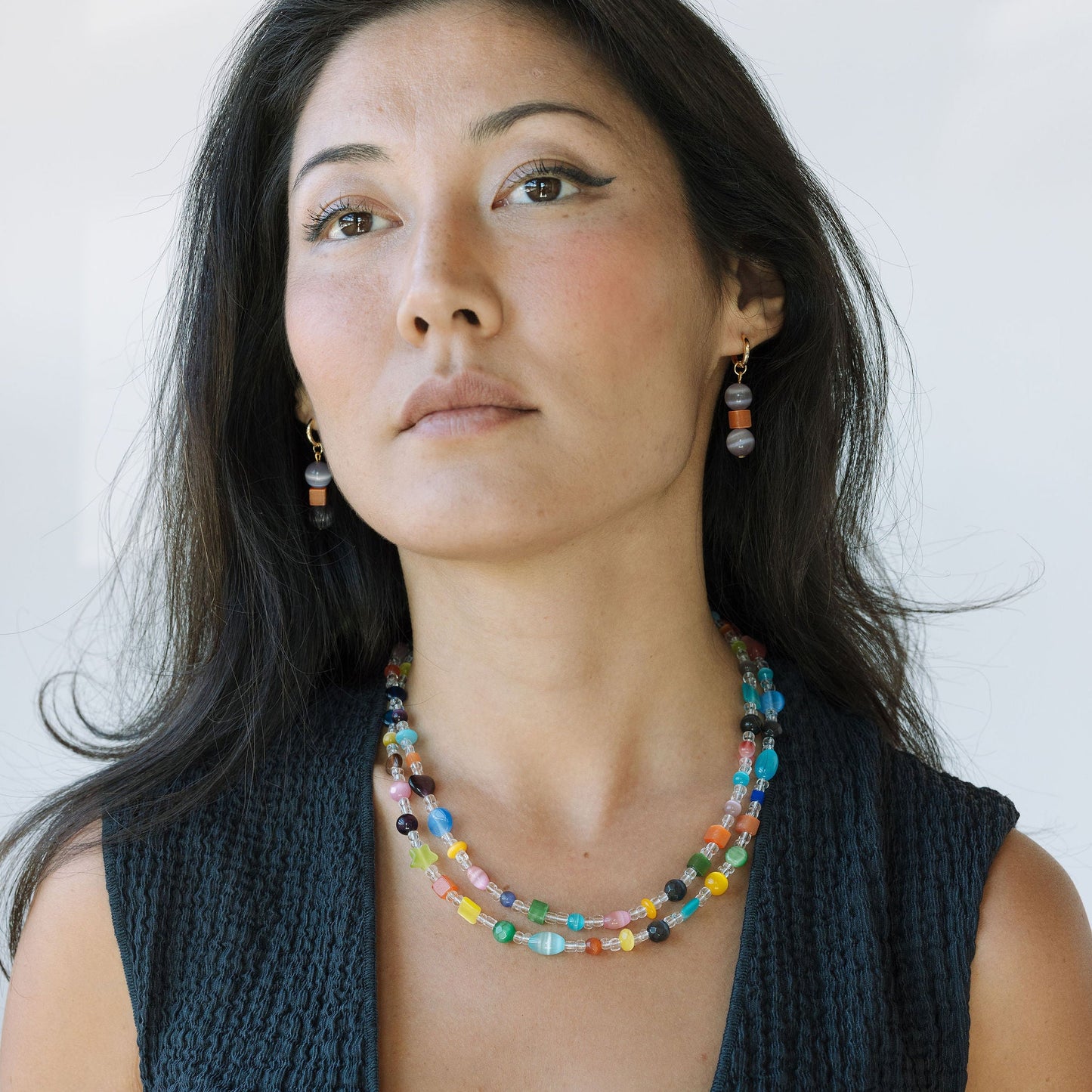 Woman wearing a colorful beaded necklace and earrings against a plain background