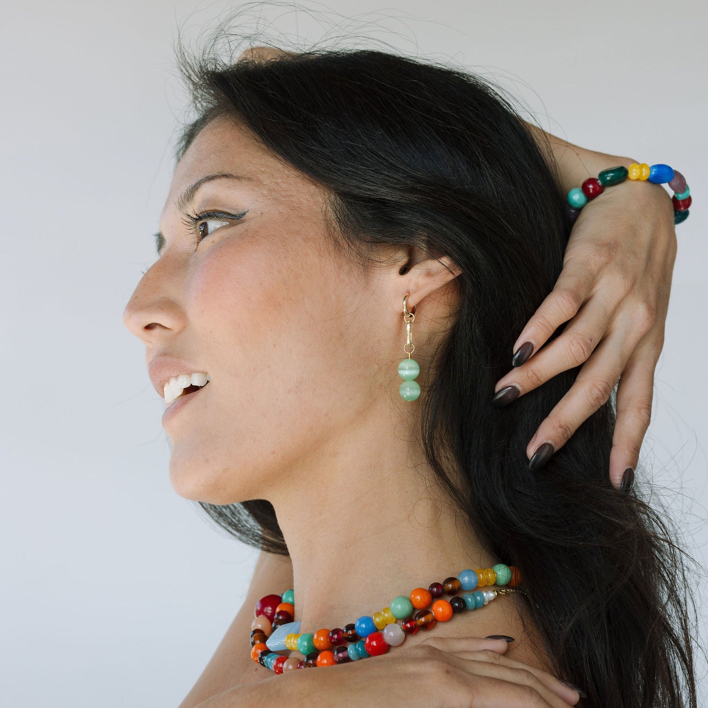 Woman wearing colorful beaded jewelry against a white background