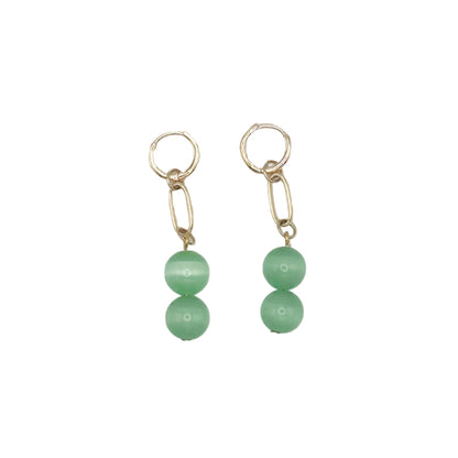 Pair of earrings with green beads on a light gray background