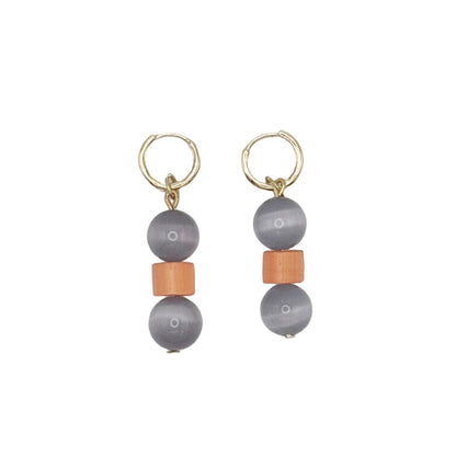 Pair of earrings with gray beads and orange accents on a light gray background