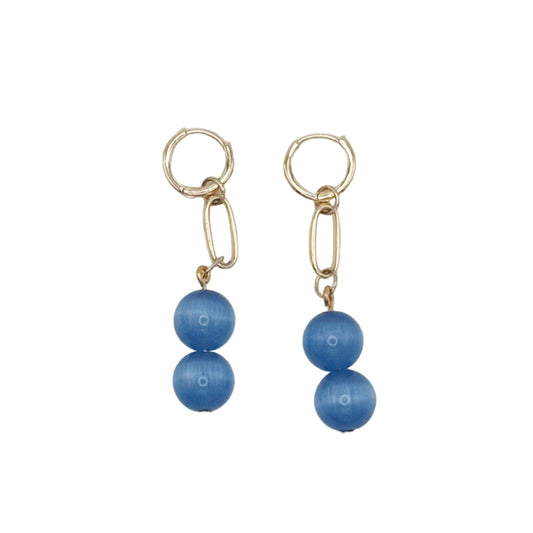 Pair of gold earrings with blue beads on a light gray background