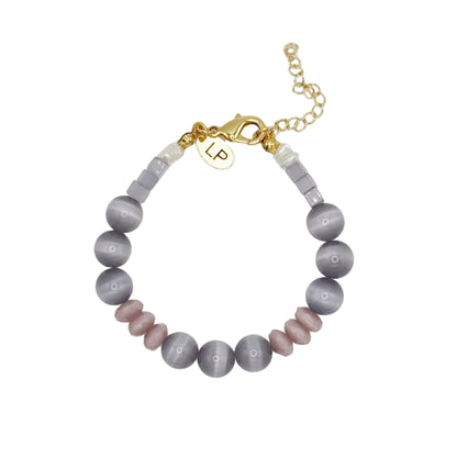 Beaded bracelet with gold charm and initials on a light gray background