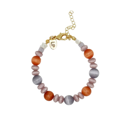 Beaded bracelet with multicolored beads and a gold charm on a light gray background