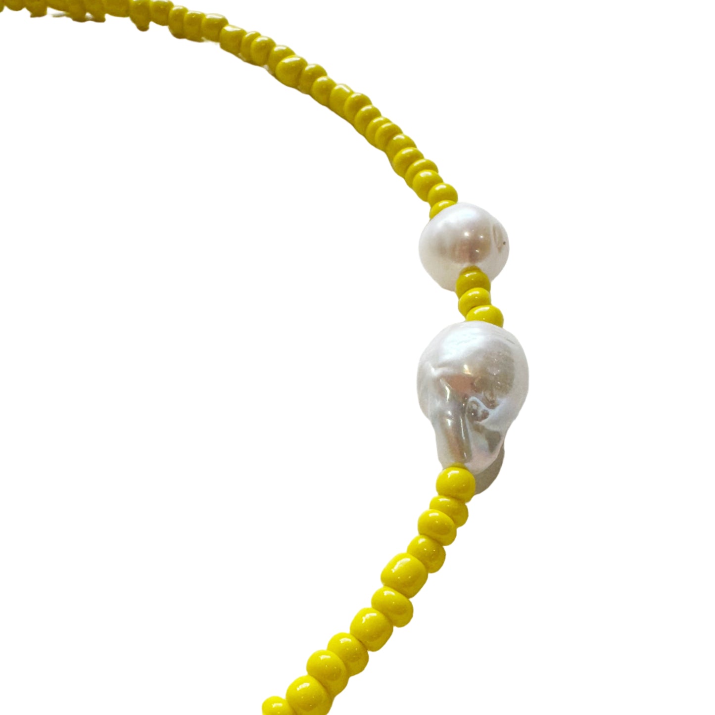 Necklace with yellow beads and white pearls on a light gray background