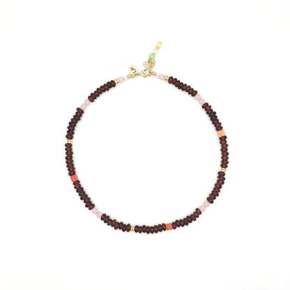 Beaded necklace with red and pink beads on a white background