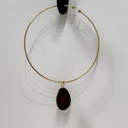 Gold hoop necklace with a dark brown teardrop pendant on a white background