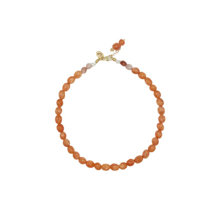 Orange beaded necklace with a gold clasp on a light gray background