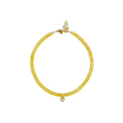 Yellow beaded bracelet with a heart charm on a white background