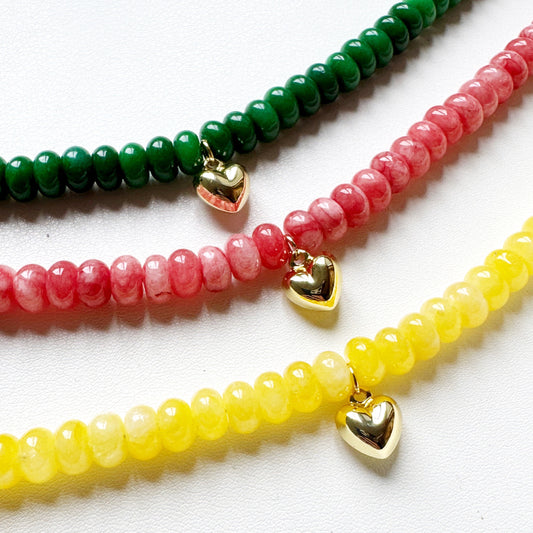 Three beaded necklaces with heart-shaped charms on a white background