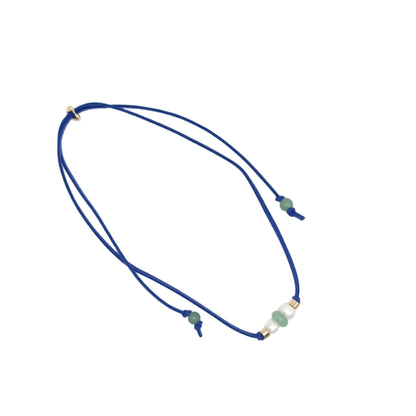 A double-strand navy blue cord necklace with small green beads and gold spacer rings, displayed on a clean white background.
