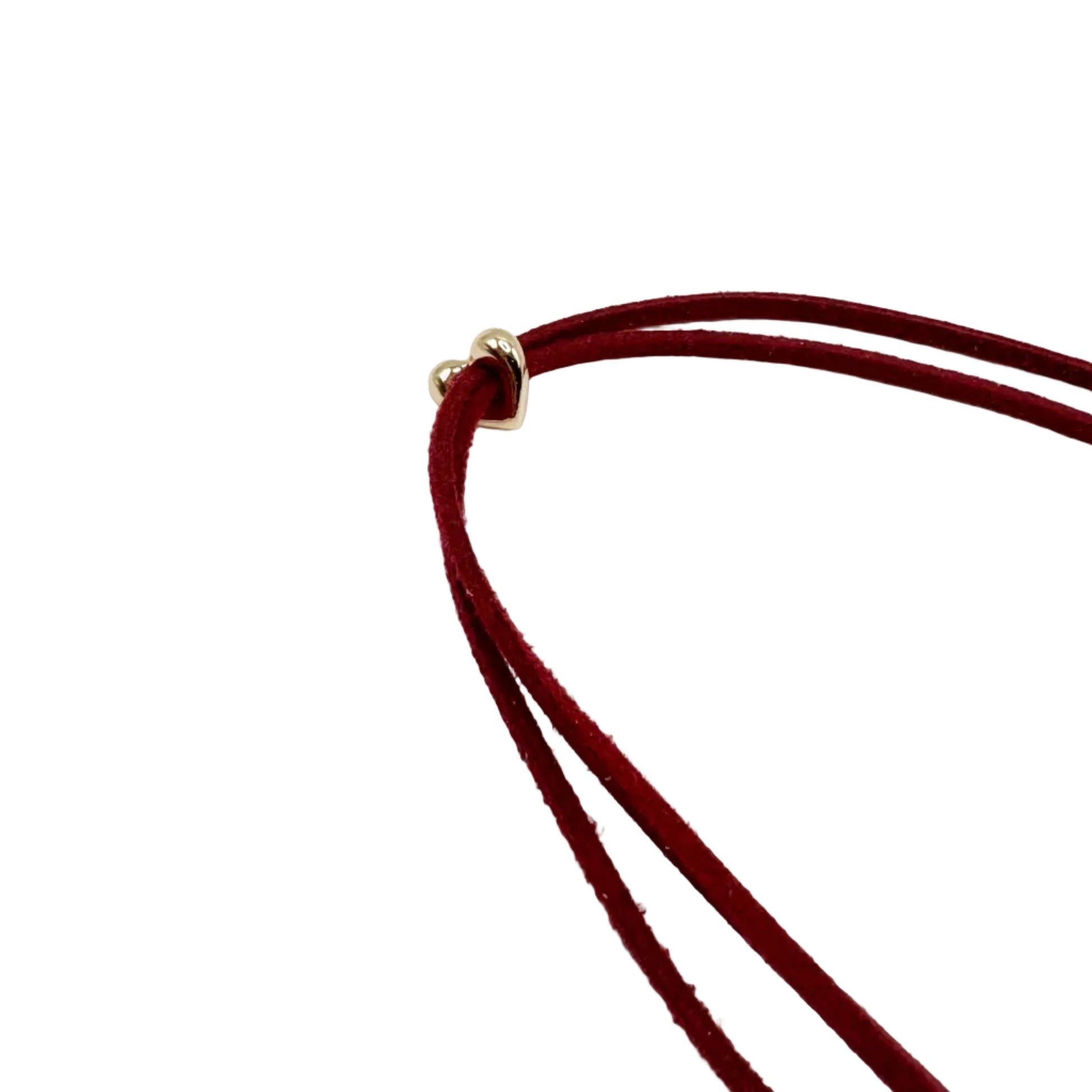 A close-up of a double-strand dark red velvet necklace with a small gold heart-shaped clasp, set against a plain white background.