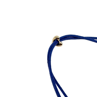 A close-up of a dark blue multi-strand cord necklace with a small gold heart-shaped charm, set against a plain white background.