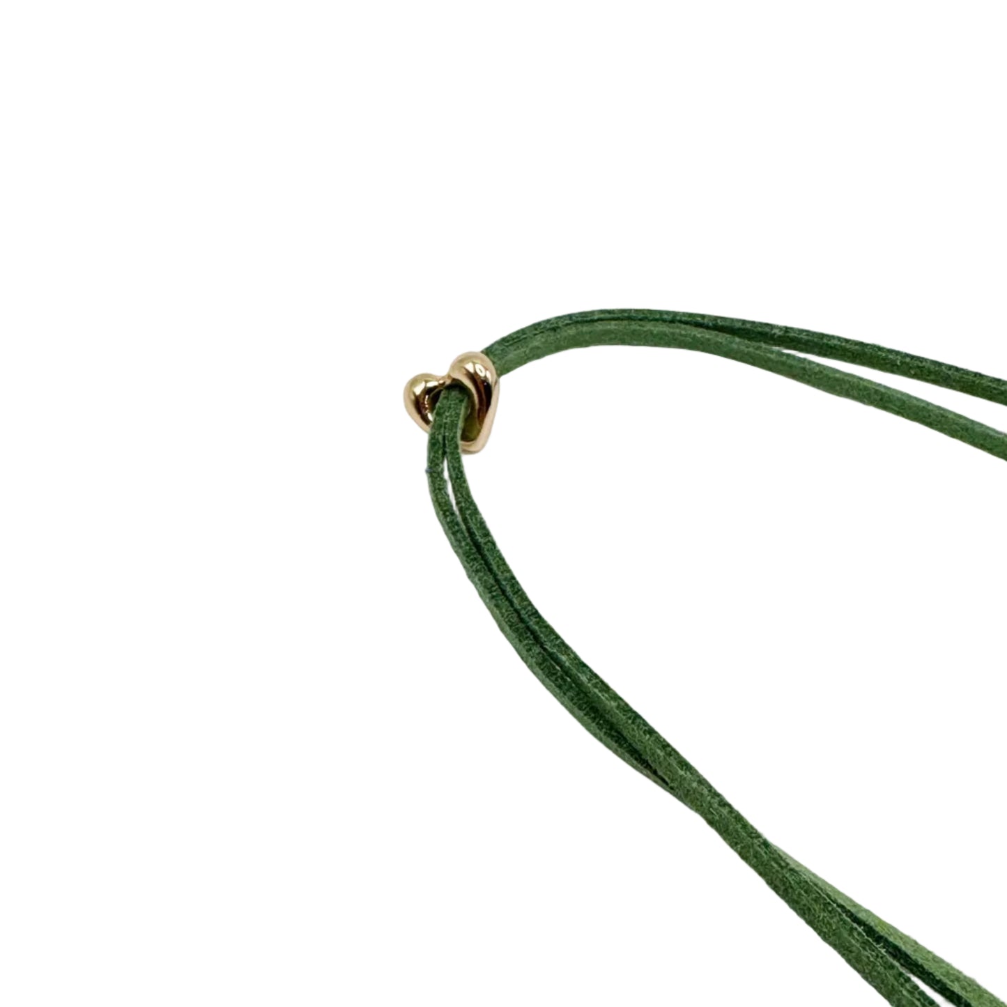 A close-up of a green suede cord necklace with a small gold heart-shaped clasp, set against a plain white background.