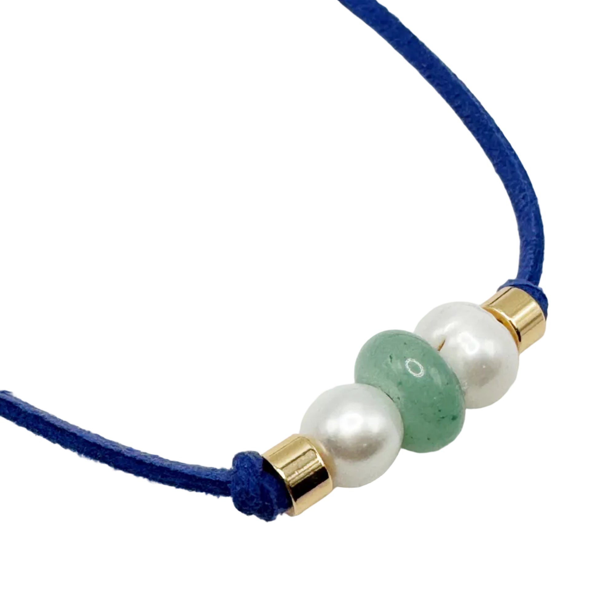 A close-up of a blue cord necklace featuring three central beads: two white faux pearls and one green jade bead, accented with gold spacers, on a white background.