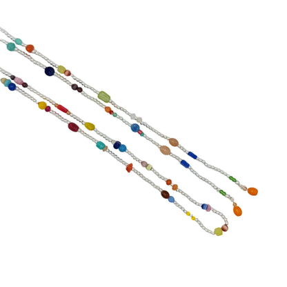 A long silver chain necklace with multiple strands of colorful glass beads, laid diagonally on a plain white background.