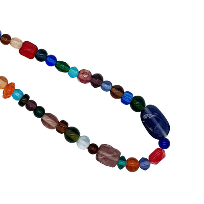 A multicolor beaded necklace made of polished, faceted gemstone beads in various colors including blue, green, red, orange, purple, and brown, arranged in a loop on a white background.