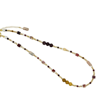 A beaded necklace with a mix of brown, gold, and burgundy beads, featuring a gold clasp and extender chain, displayed on a clean white background.