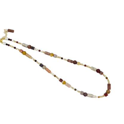 A beaded necklace with a mix of brown, cream, yellow, and dark red beads, featuring a gold clasp, displayed on a clean white background.