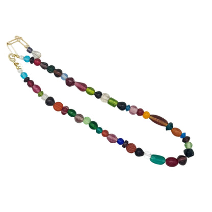 A beaded strand necklace with a gold clasp, featuring a mix of colorful oval and round beads in green, red, blue, purple, orange, and black, displayed on a plain white background.