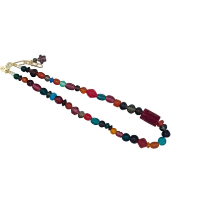 A multi-colored beaded necklace with a gold clasp, featuring faceted beads in shades of red, orange, green, blue, and purple, displayed on a clean white background.