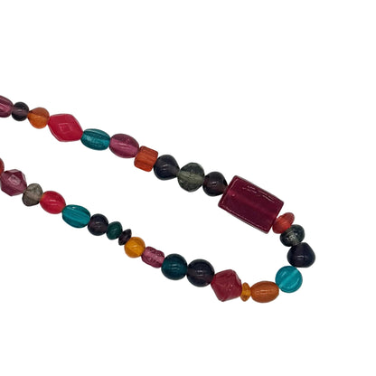 A beaded necklace made of polished, faceted gemstone beads in multiple colors including red, teal, orange, black, and gray, arranged in two loops on a plain white background.