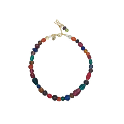 A beaded necklace with multicolored oval and round beads, accented by small gold spacer beads and a gold toggle clasp, displayed on a light gray background.