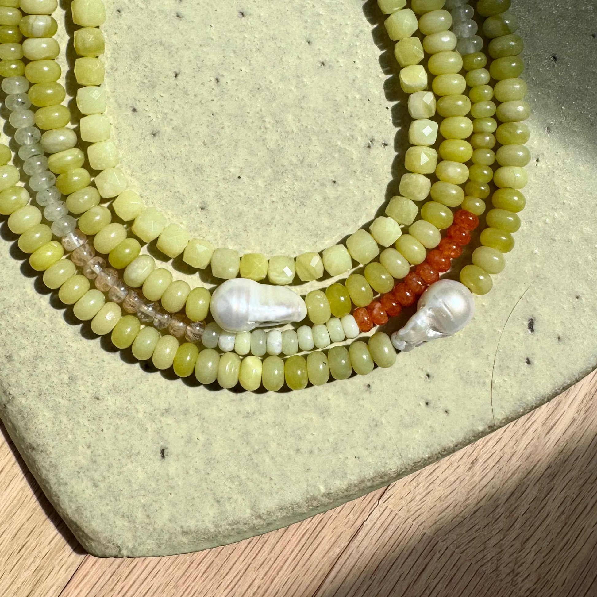 Necklace with green and red beads on a textured surface