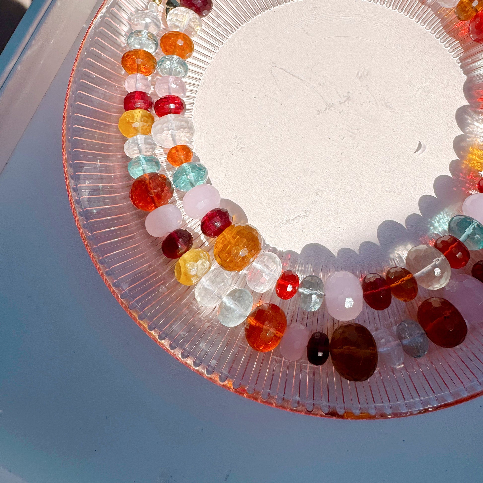 Clear glass plate with colorful beads on a white surface