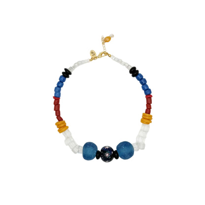 A beaded necklace with a mix of translucent white beads, blue beads, red beads, yellow-orange beads, and black spacer beads, featuring a central dark blue and black bead motif, displayed on a clean white background.