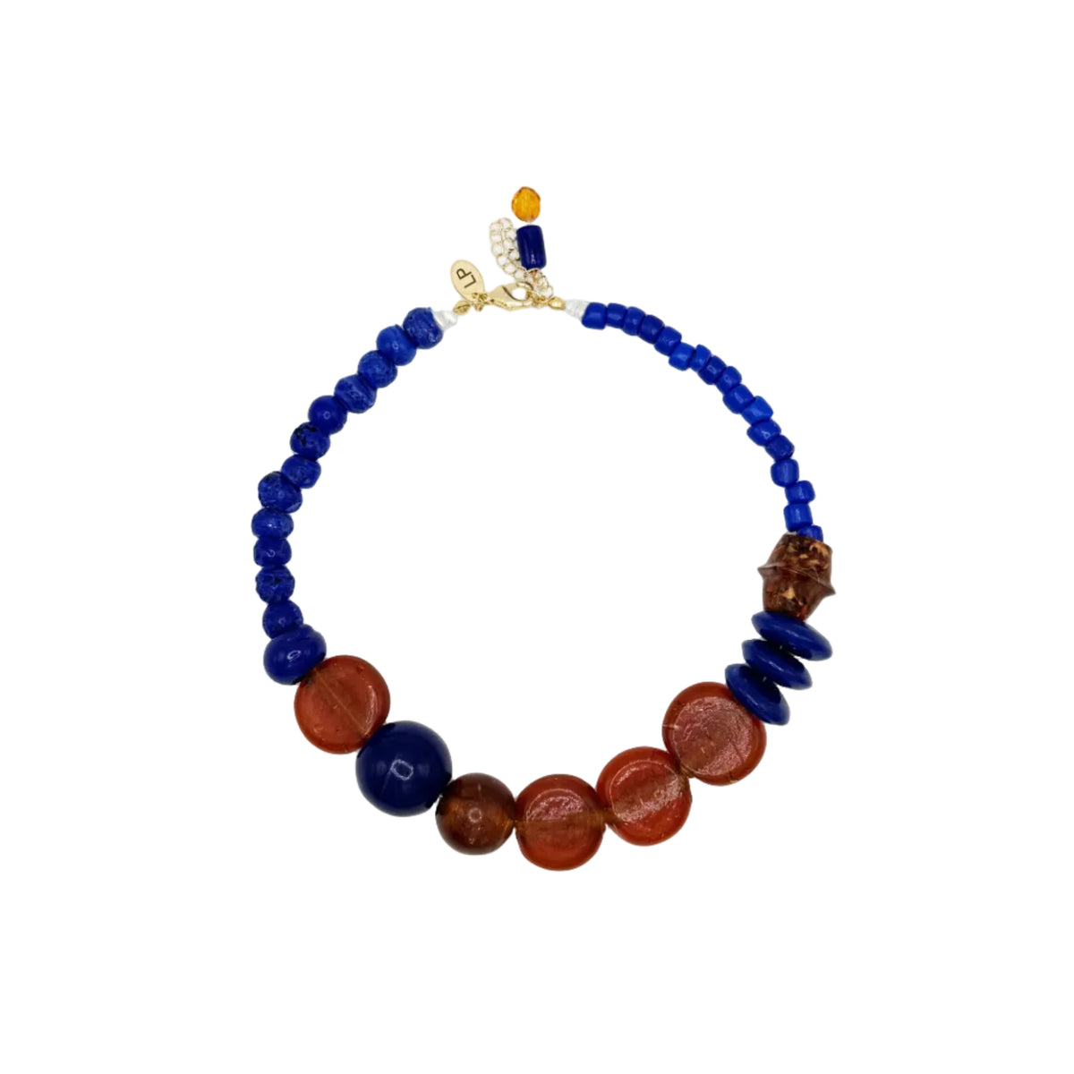 A beaded necklace featuring deep blue glass beads, polished red and brown stone beads, and a gold-toned clasp with a small orange bead accent, displayed on a clean white background.