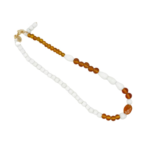 A beaded necklace featuring white square beads, translucent amber brown round beads, and a small gold clasp, displayed on a plain white background.