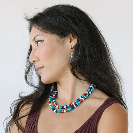 Woman wearing a colorful beaded necklace against a white background