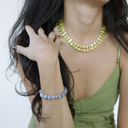 Woman wearing a green dress with jewelry including a necklace, bracelet, and ring.