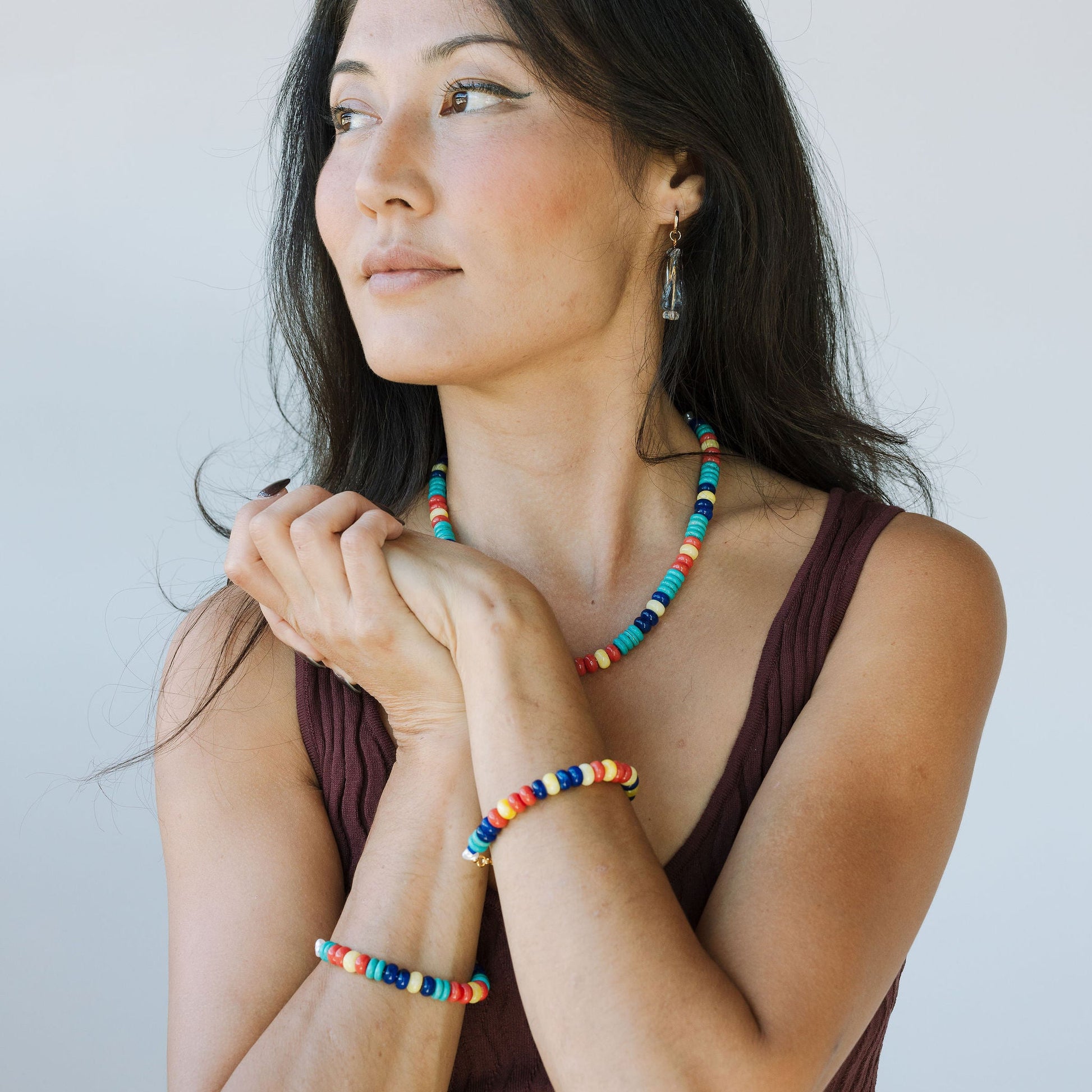 Woman wearing colorful beaded necklaces and bracelets against a plain background