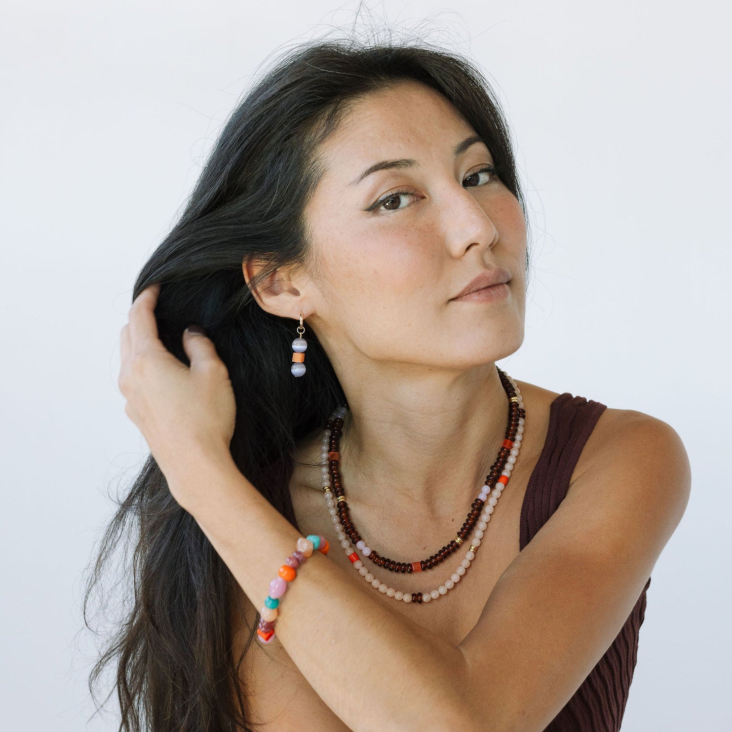 Woman wearing a necklace with colorful beads against a white background