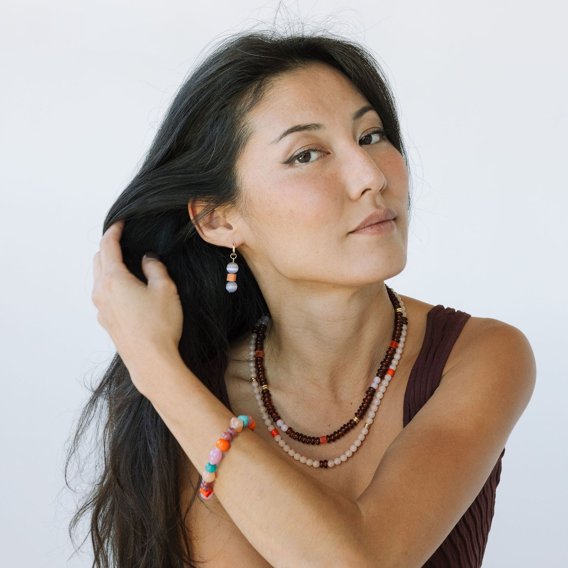 Woman wearing a necklace with colorful beads against a white background