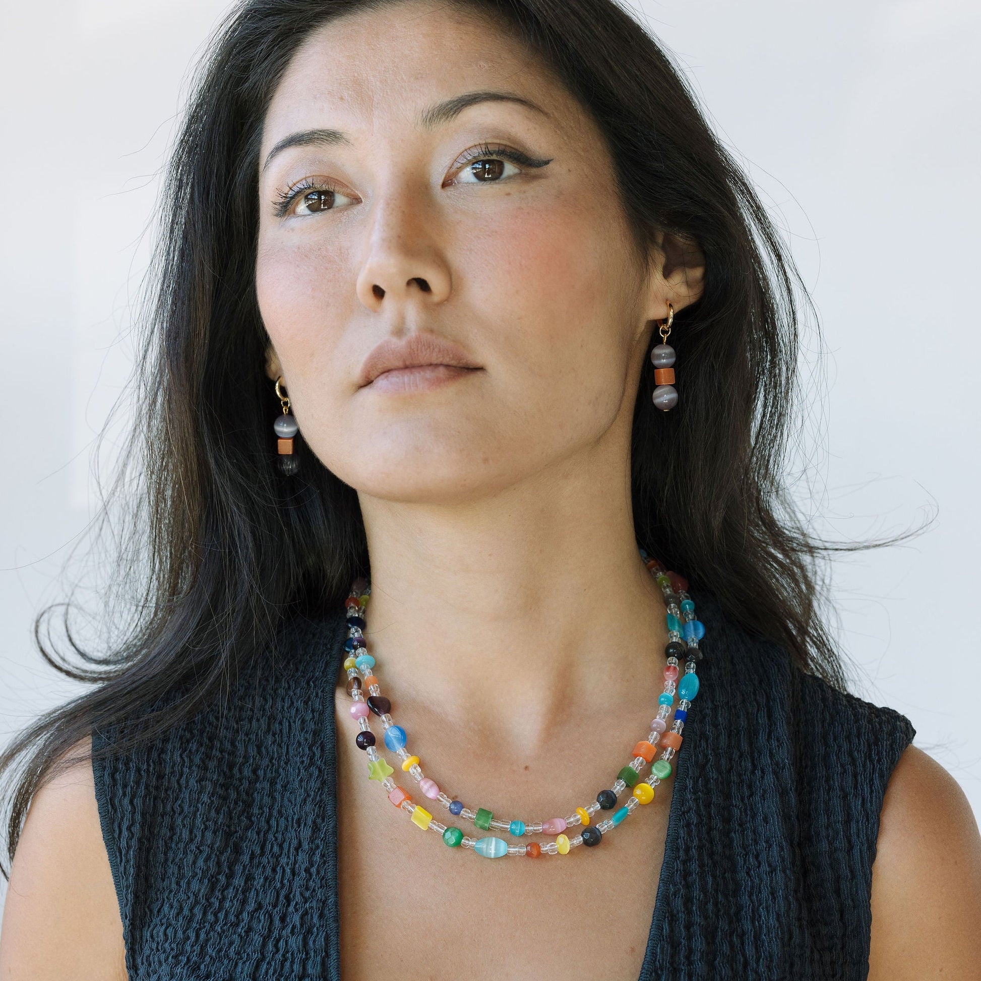 Woman wearing a colorful beaded necklace and earrings against a plain background