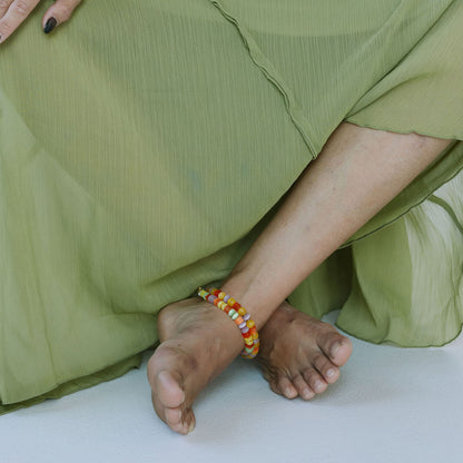 Person wearing a green dress with visible feet and bracelets on a white background