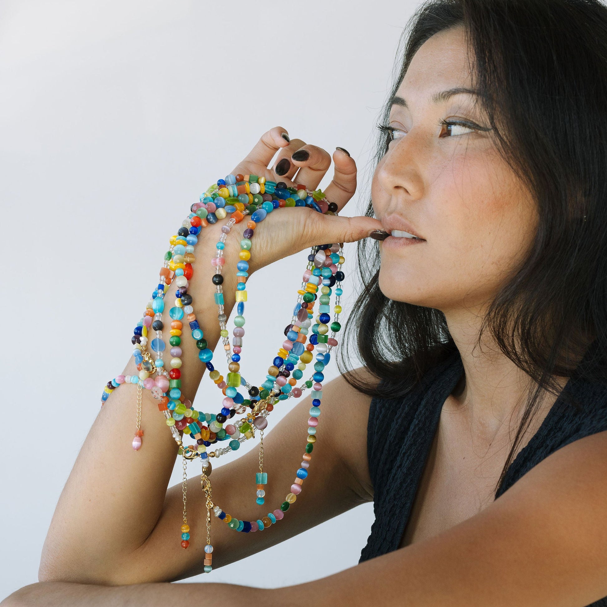Woman holding colorful beaded necklaces against a white background