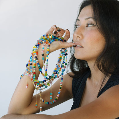 Woman holding colorful beaded necklaces against a white background