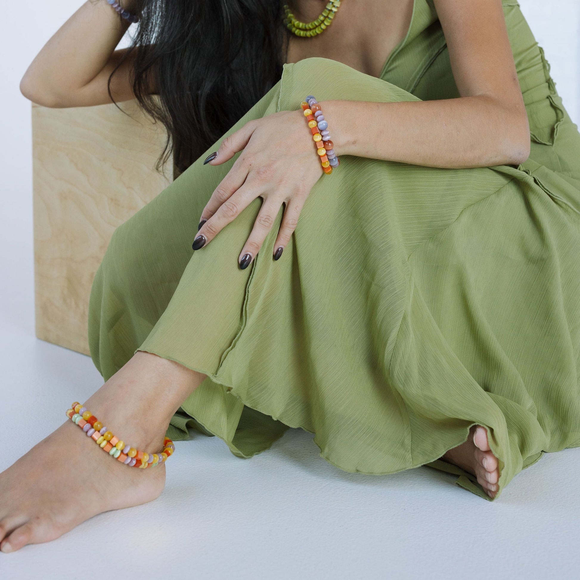 Woman in a green dress sitting on a white background
