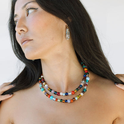 Woman wearing a colorful beaded necklace and earrings against a plain background