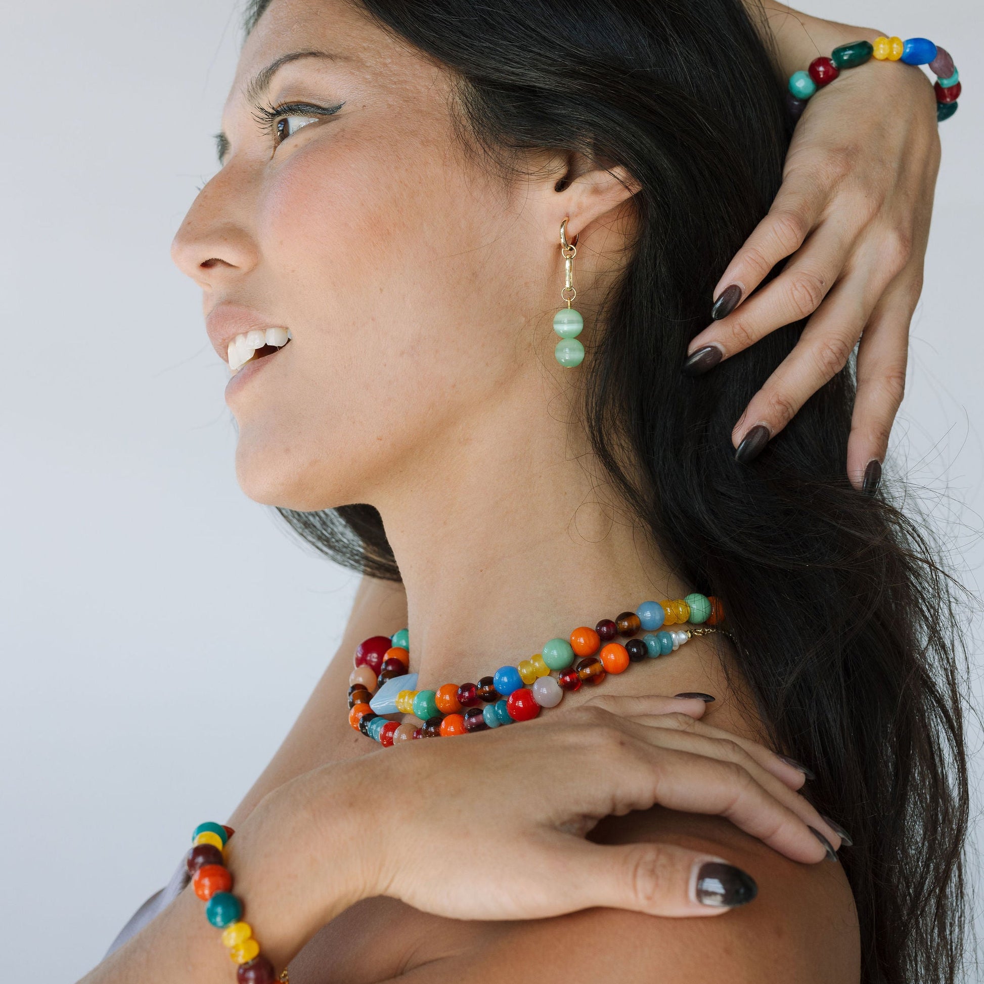 Woman wearing colorful beaded jewelry against a white background