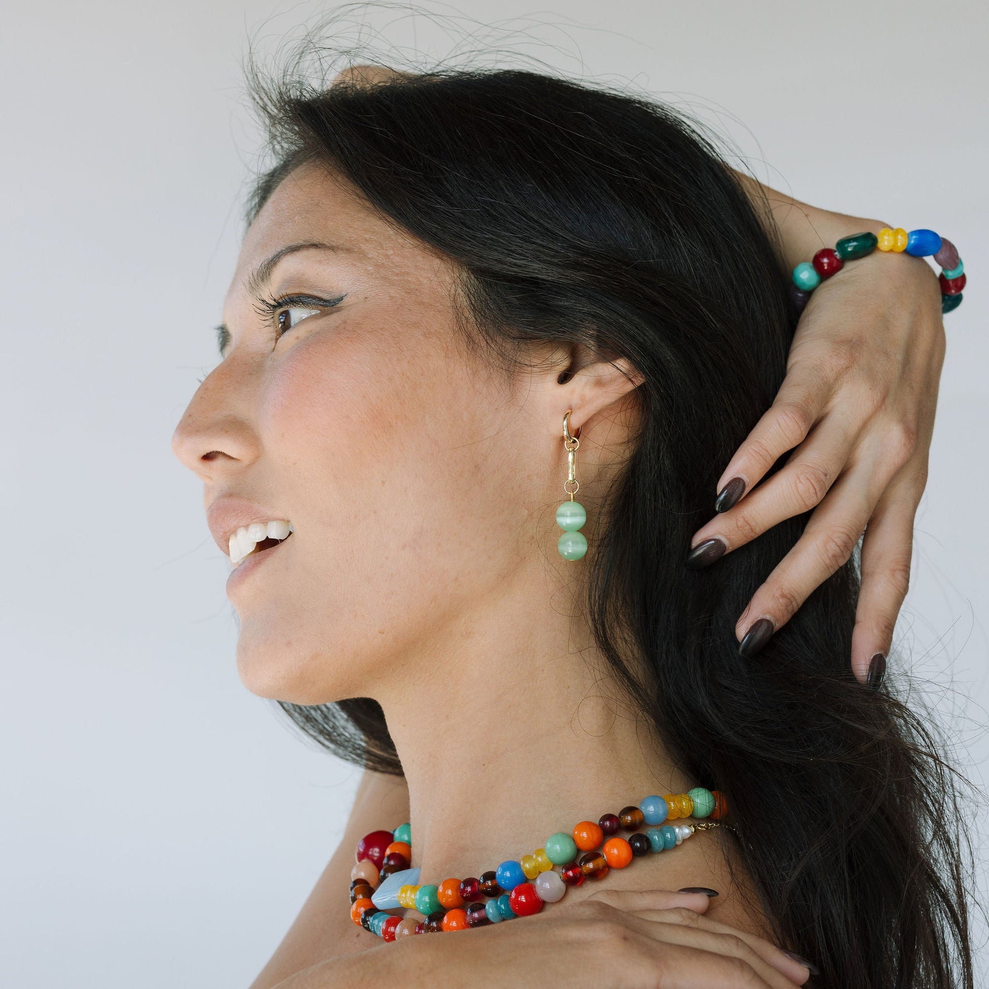 Woman wearing colorful beaded jewelry against a white background