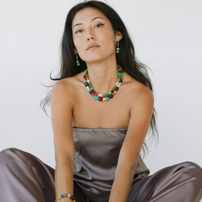 Woman wearing a colorful beaded necklace and bracelets on a white background