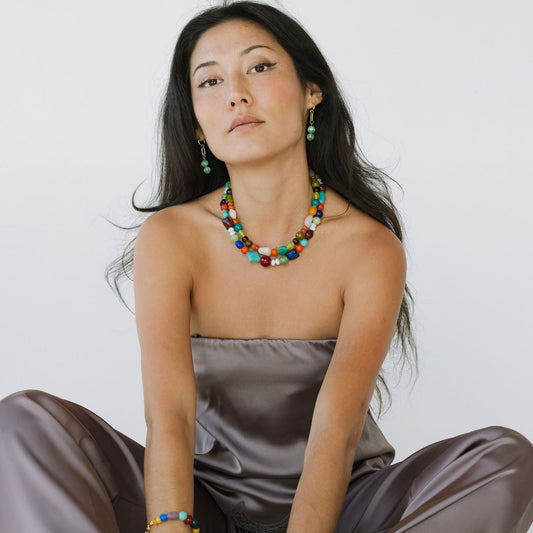 Woman wearing a colorful beaded necklace and bracelets on a white background