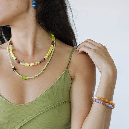 Woman wearing a green top with colorful beaded necklaces and bracelets on a white background